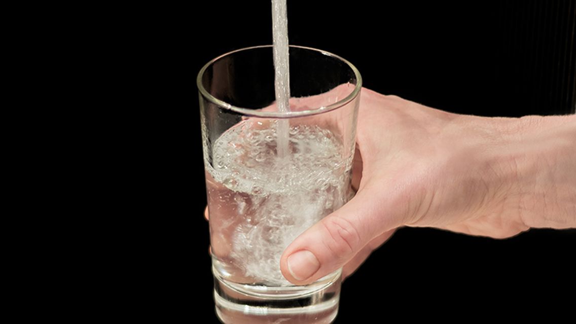 ein Glas wird mit Trinkwasser gefüllt